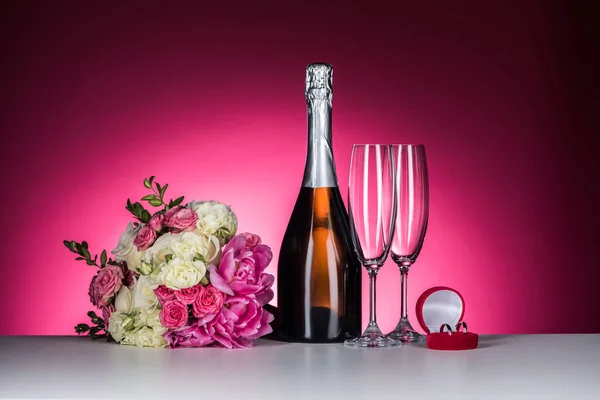 Bouquet da sposa, fedi nuziali e champagne su rosa — Foto stock