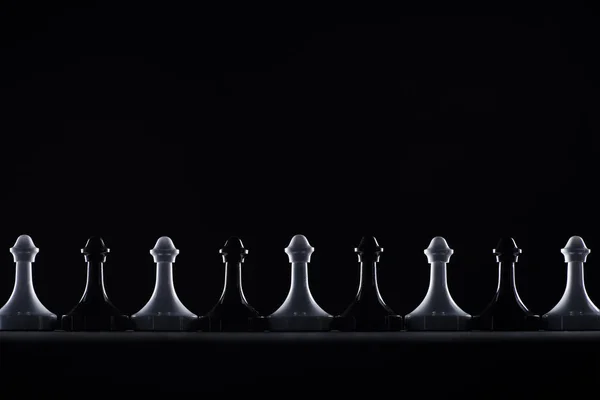 Siluetas de peones de ajedrez en blanco y negro aislados en negro, concepto de negocio — Stock Photo