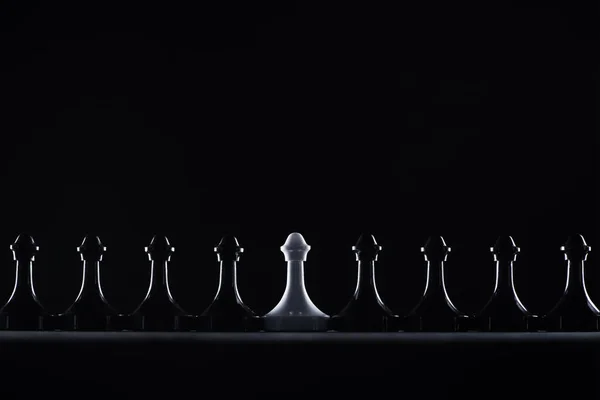 Silhouettes de pions d'échecs noirs et blancs isolés sur noir, concept d'affaires — Photo de stock