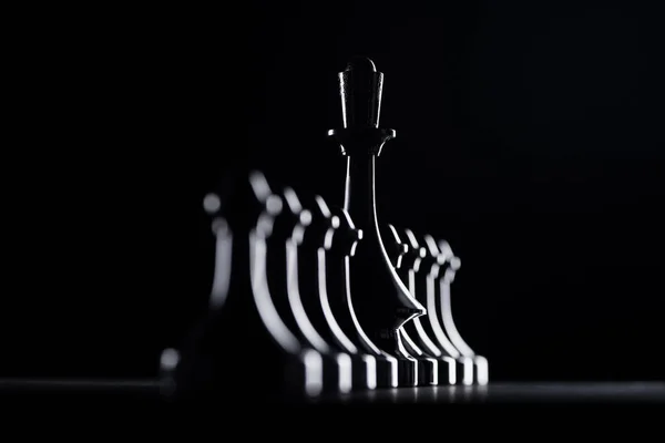 Silhouettes of chess pawns and queen isolated on black, business concept — Stock Photo