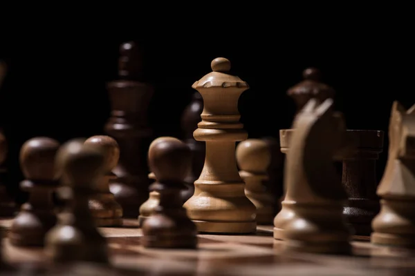 Дерев'яні шахові фігури на шахівниці ізольовані на чорному, бізнес-концепція — стокове фото