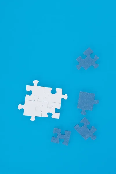 Vue de dessus des puzzles blancs et bleus isolés sur bleu, concept d'entreprise — Photo de stock