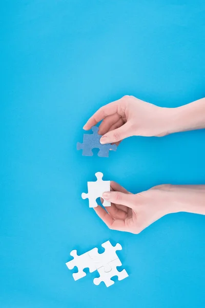 Cropped image of businesswoman assembling blue and white puzzles isolated on blue, business concept — Stock Photo