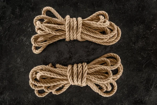 Top view of arrangement of tied brown marine ropes on dark concrete surface — Stock Photo