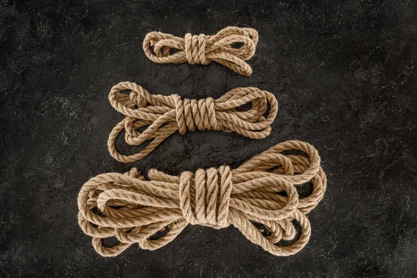 Top view of arrangement of tied brown marine ropes on dark concrete surface — Stock Photo