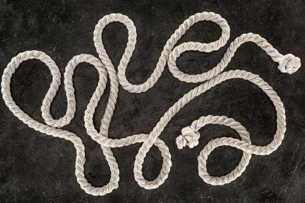 Top view of white nautical rope with knots on dark concrete tabletop — Stock Photo