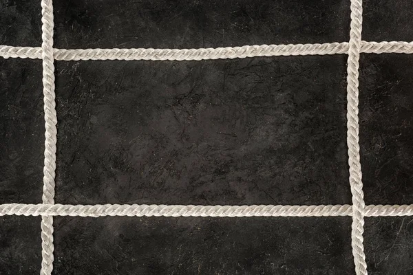 Vista superior de cordas marinhas brancas dispostas em mesa de concreto escuro — Fotografia de Stock