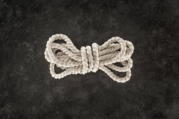 Top view of tied white nautical rope on dark concrete tabletop — Stock Photo