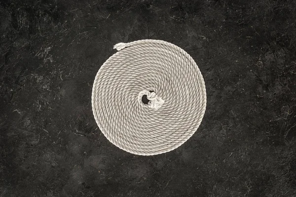 Top view of white nautical rope arranged in circle on dark concrete tabletop — Stock Photo