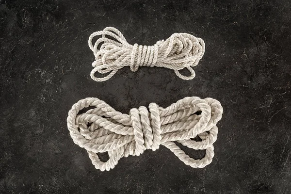 Top view of arranged tied white marine ropes on dark concrete tabletop — Stock Photo