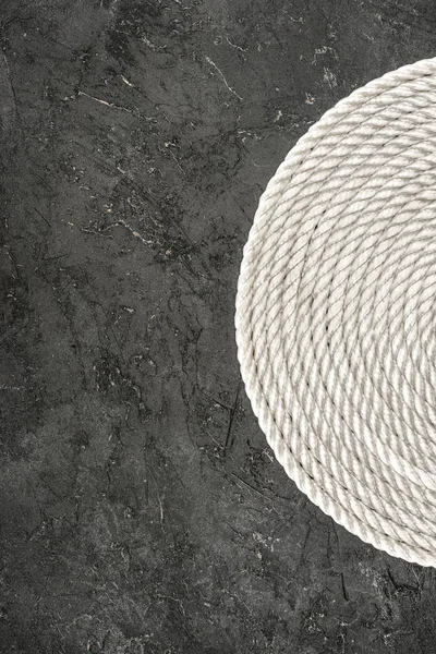 Top view of white nautical rope arranged in circle on dark concrete tabletop — Stock Photo