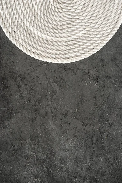 Top view of white nautical rope arranged in circle on dark concrete tabletop — Stock Photo