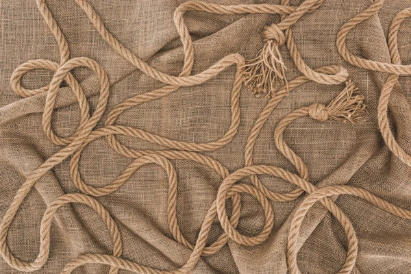 Top view of arranged brown nautical rope with knots on sackcloth — Stock Photo