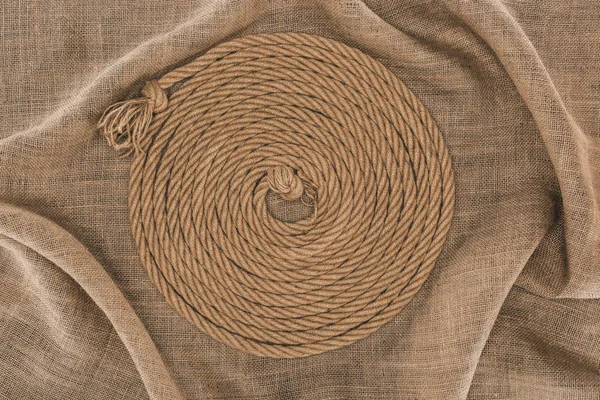 Top view of brown nautical rope arranged in circle on sackcloth — Stock Photo