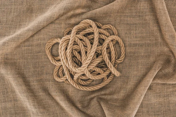 Vista superior de cuerda náutica marrón arreglada sobre tela de saco - foto de stock