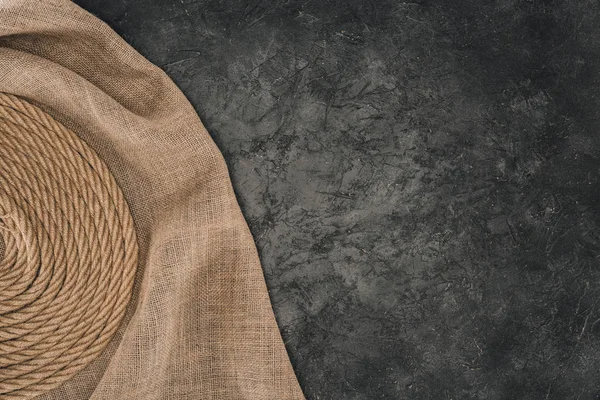 Top view of brown nautical rope arranged in circle on sackcloth on dark concrete tabletop — Stock Photo