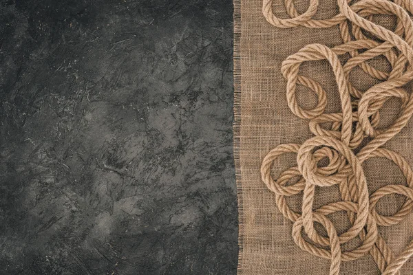 Вид зверху розташована коричнева морська мотузка на мішковині на темній бетонній стільниці — стокове фото
