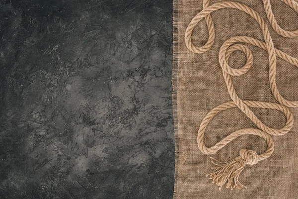 Top view of arranged brown nautical rope on sackcloth on dark concrete tabletop — Stock Photo