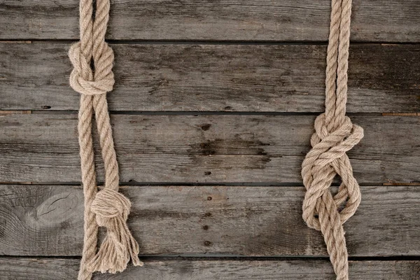 Deitado plano com cordas marinhas com nós na mesa de madeira grunge — Fotografia de Stock