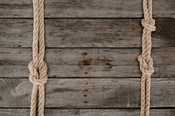 Deitado plano com cordas marinhas com nós na mesa de madeira grunge — Fotografia de Stock