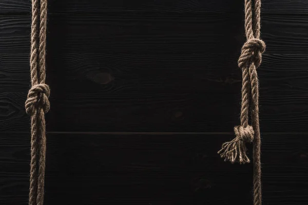 Draufsicht auf die Anordnung brauner nautischer Seile mit Knoten auf dunkler Holztischplatte — Stockfoto