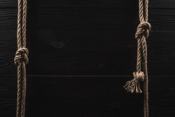 Top view of arrangement of brown nautical ropes with knots on dark wooden tabletop — Stock Photo