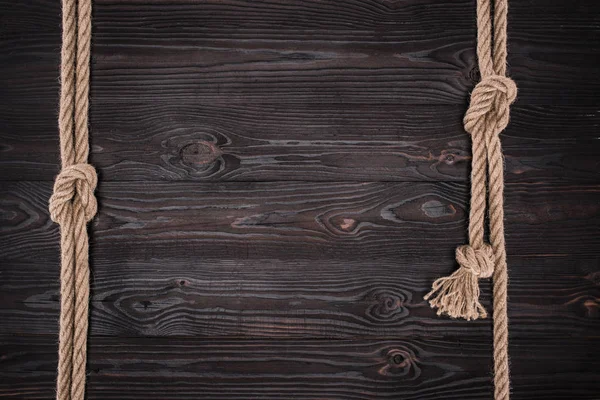 Vista dall'alto di disposizione di corde nautiche marroni con nodi su tavolo di legno scuro — Foto stock