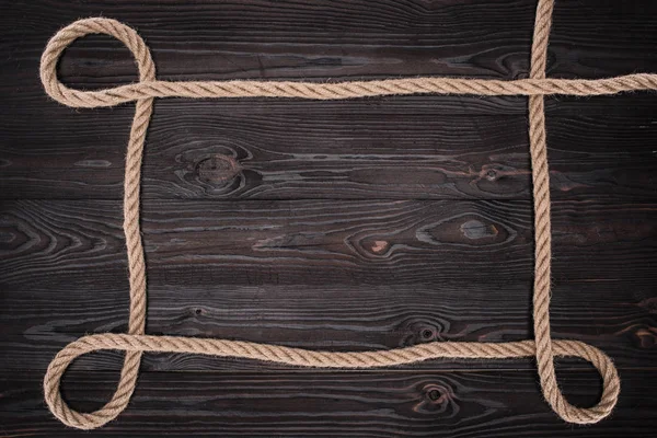 Vue de dessus de corde nautique marron sur une surface en bois sombre — Photo de stock