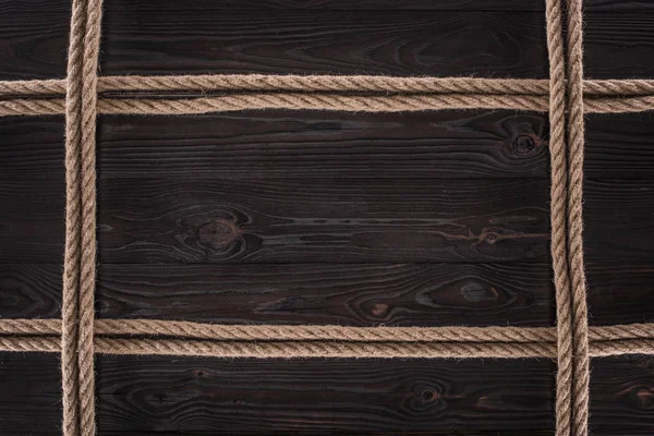 Vista superior de arranjo de cordas náuticas marrons em mesa de madeira escura — Fotografia de Stock