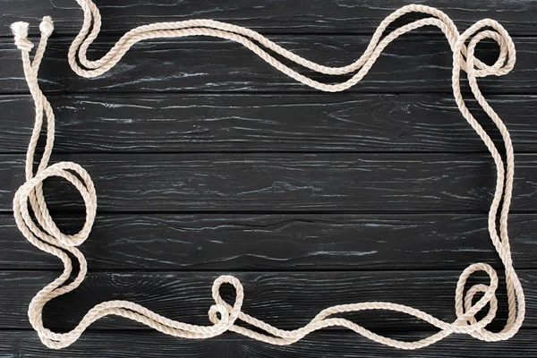 Top view of arranged white marine ropes with knots on dark wooden tabletop — Stock Photo