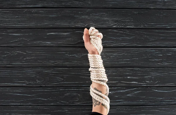 Partial view of female hand with marine rope on dark wooden surface — Stock Photo