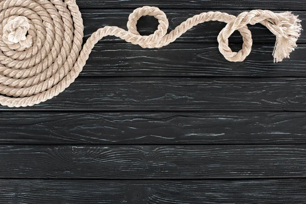 Верхний вид белой морской веревки, расположенной по кругу на темной деревянной столешнице — стоковое фото
