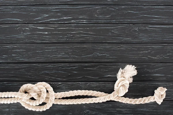 Top view of white nautical rope with knots on dark wooden tabletop — Stock Photo