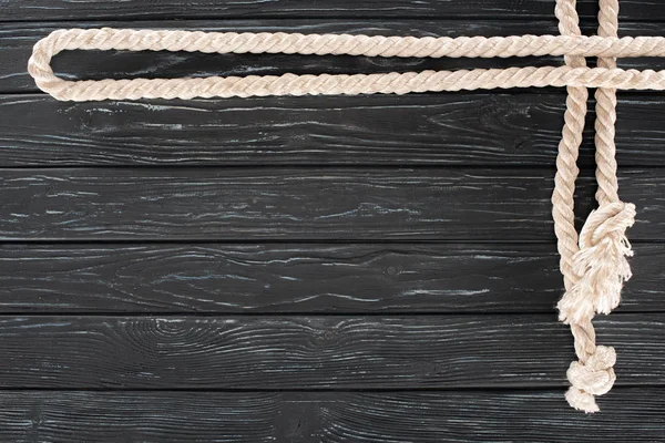 Top view of white nautical rope with knots on dark wooden tabletop — Stock Photo