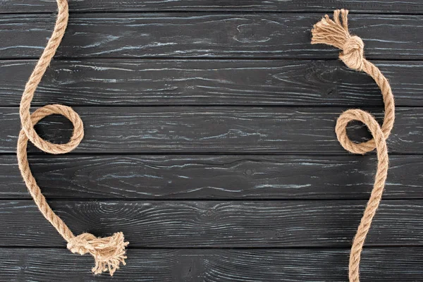 Top view of brown ropes with knots on dark wooden surface — Stock Photo