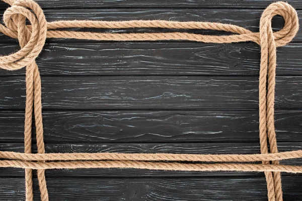 Вид сверху на коричневые веревки на темной деревянной поверхности — стоковое фото