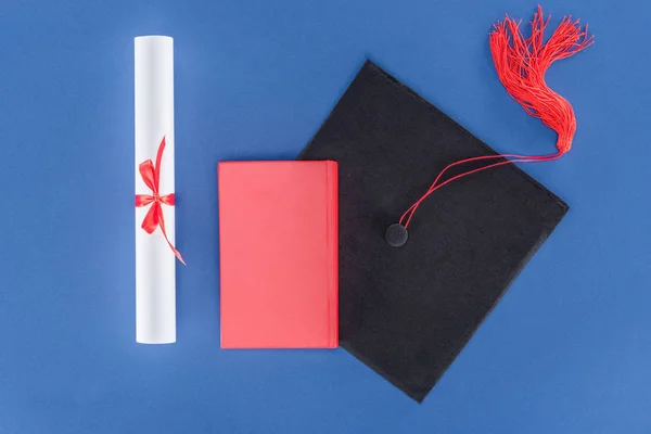 Capa de graduação com diploma e livro isolado em azul — Fotografia de Stock