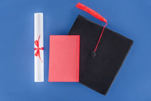 Концепція освіти з дипломом та випускною кепкою ізольована на синьому — стокове фото