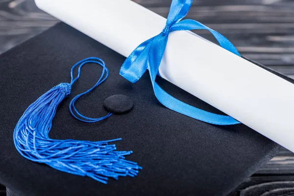 Conceito do ensino médio com diploma e tampa de graduação em mesa de madeira — Fotografia de Stock