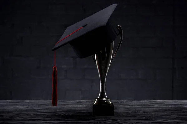 Tapa de graduación en copa de trofeo en mesa de madera - foto de stock