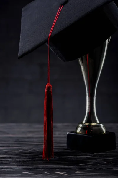 Coupe trophée avec tasse de graduation sur table en bois — Photo de stock