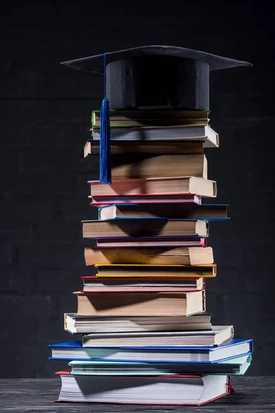 Boné de graduação na torre de livros empilhados — Fotografia de Stock