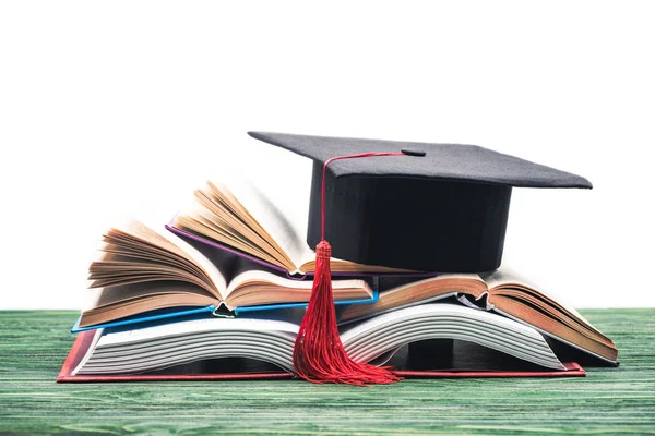 Berretto di laurea su pila di libri aperti — Foto stock