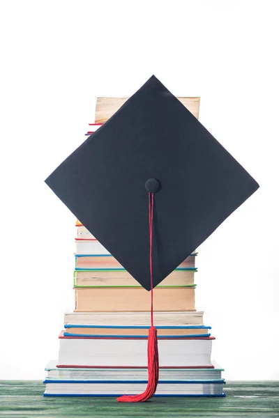 Graduation cap in front of stacked books — Stock Photo