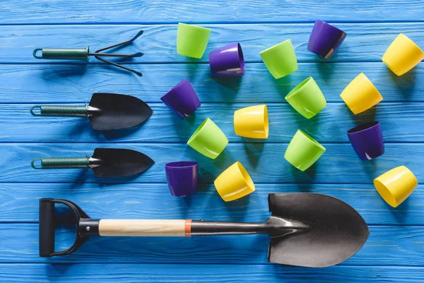 Top view of gardening equipment and colorful flower pots on blue wooden planks — Stock Photo