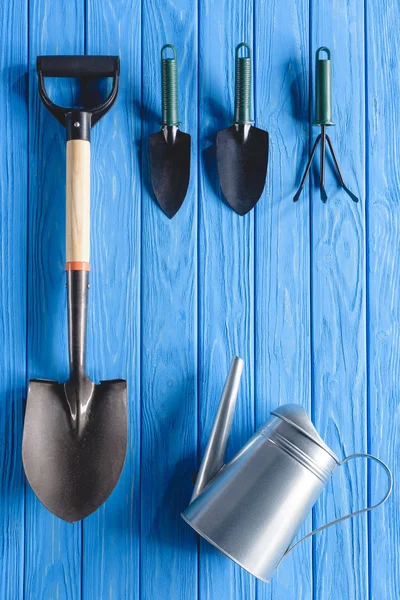 Draufsicht auf Gießkanne und Gartengeräte auf blauen Holzplanken — Stockfoto