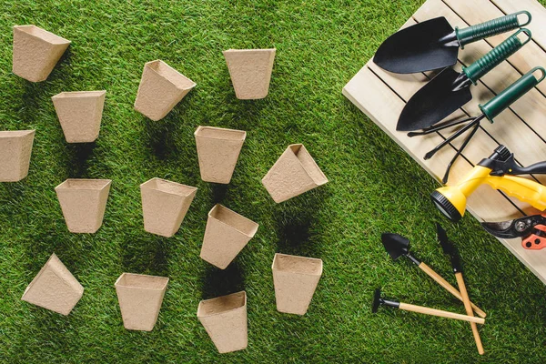 Top view of gardening equipment and pile of flower pots on grass — Stock Photo