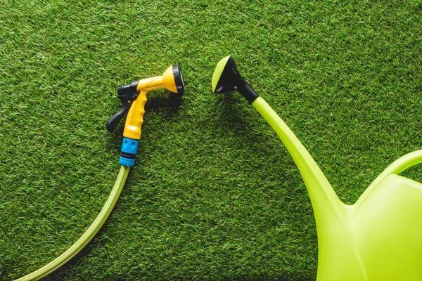 Draufsicht auf Gießkanne und Schlauchleitung im Gras, minimalistische Konzeption — Stockfoto