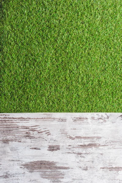 Top view of green lawn and wooden planks background — Stock Photo