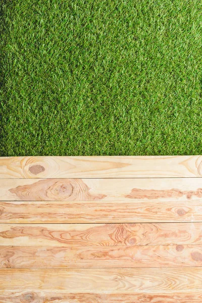 Vista superior del césped verde y los tablones de madera de fondo - foto de stock